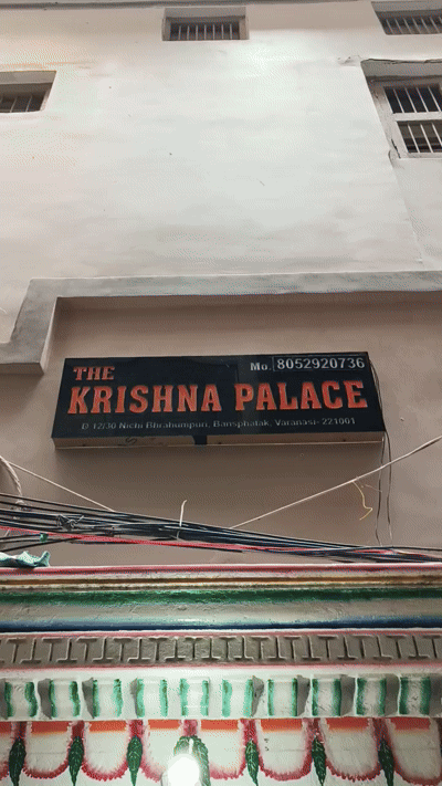 A dressed guest room at Krishna Palace with a wooden ceiling, pendant light and a red-and-cream rug.