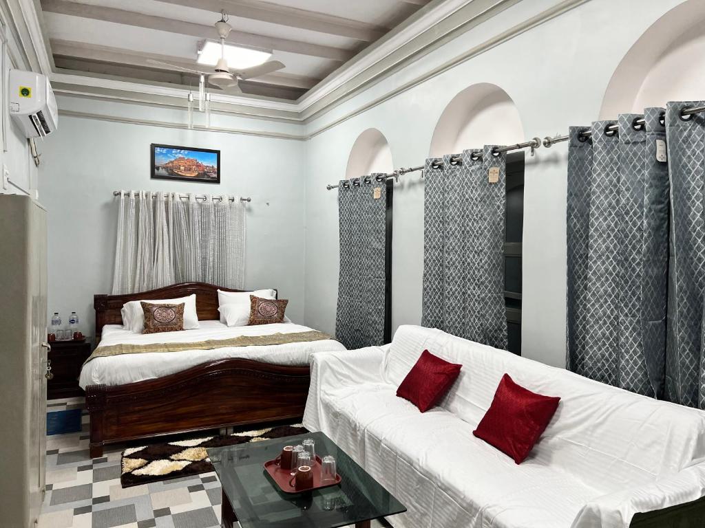 The Deluxe Room at Krishna Palace, with arched alcoves, a dressed bed and a white sofa with red cushions.